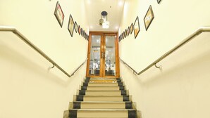 A staircase with a handrail, leading to a door with glass panels. - Fabhotel Motisarai (Kolkata)
