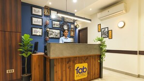 A reception desk with a wooden finish, a 'fab hotels' logo, and framed pictures on the wall. - Fabhotel Motisarai (Kolkata)