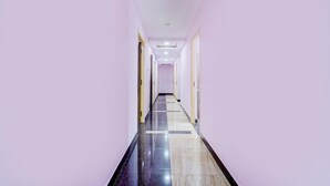 A long, narrow hallway with a checkered floor pattern, leading to a door at the end. - Fabhotel Sahana Residency (Chennai)