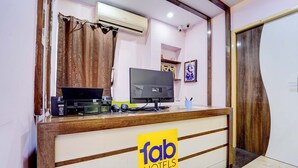 A hotel reception desk with a computer, a television, and a sign for 'fab hotels'. - Fabhotel Sahana Residency (Chennai)