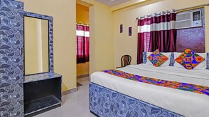Un dormitorio con cama, una silla, un espejo y una ventana con cortinas.