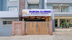 A building with a sign reading "PuruDA Classes IIT-JEE | NEET | FOUNDATION". - FabHotel The Tuesday Suits - Opposite to Delhi Public School (Noida)