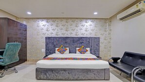 A hotel room with a bed, a desk, a chair, and a sofa. - FabHotel The Tuesday Suits - Opposite to Delhi Public School (Noida)