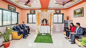 A reception area with a floral altar, seating arrangements, and ceiling fans. - FabExpress Abhishek (Pune)