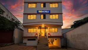 A multi-story building with a 'fabHOTELS' sign, a staircase leading to the entrance, and a gated driveway. - FabExpress Abhishek (Pune)