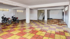 A spacious indoor parking area with a checkered floor pattern, two motorcycles parked, and a staircase leading to another level. - FabExpress Abhishek (Pune)