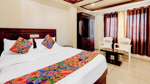 A hotel room with a large bed, a wooden headboard, a desk with a chair, and a window with curtains. - Fabhotel Alfa (Vijayawada)