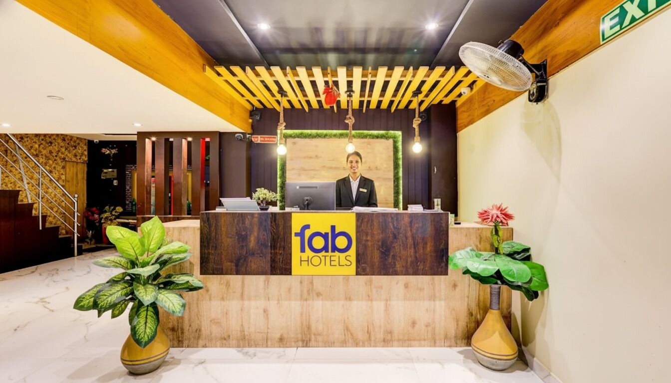 Ein Empfangsschalter mit einem Schild mit dem Schriftzug "fab hotels", einer Holzzieldecke, einem Ventilator und Blumentöpfen.