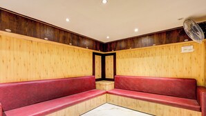 A corner seating area with wooden paneling and red cushioned benches. - Fabhotel Alfa (Vijayawada)