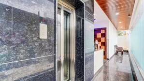 Un moderno vestíbulo de hotel con piso de mármol, techo de madera y una mesa de recepción.