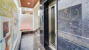 Un pasillo con piso de mármol, techo de madera y puerta de ascensor de vidrio.