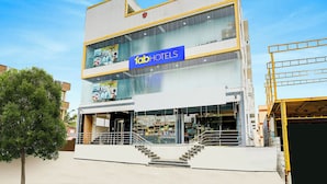 Un hotel moderno con un llamativo letrero de 'FabHotels', varios pisos y una escalera visible que lleva a la entrada.