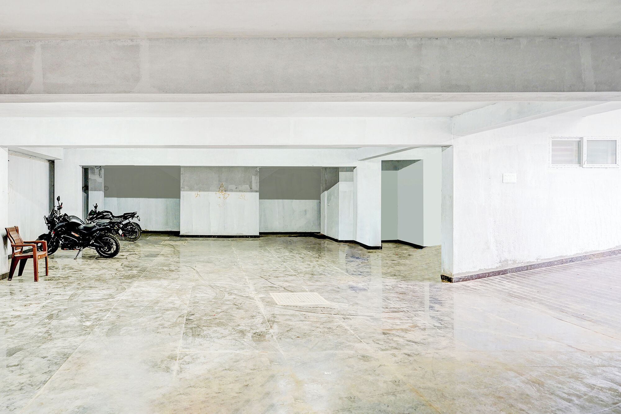 Un grand espace intérieur doté d’un sol ciré, d’une moto et d’une chaise.
