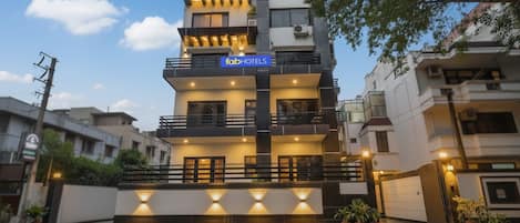 A multi-story hotel with a modern design, featuring balconies and a well-lit entrance.