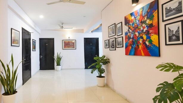 A hallway with a ceiling fan, black doors, and framed pictures on the walls. - Fabhotel X Green Tree (Gurugram)