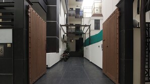 A narrow corridor with a tiled floor, flanked by wooden gates, leading to a staircase.