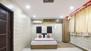 A bedroom with a bed, a wardrobe, and an air conditioning unit. - Fabhotel Park View I (New Delhi)
