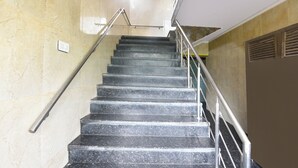 A staircase with metal railings and a handrail, leading to a landing with a light fixture. - Fabhotel Park View I (New Delhi)