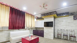 A living room with a sofa, a glass coffee table, a TV, and a ceiling fan. - Fabhotel Park View I (New Delhi)