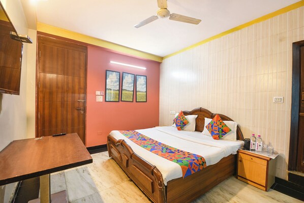 A bedroom with a bed, bedside table, and a wooden wardrobe. - Fabhotel Elegant Stay (New Delhi)