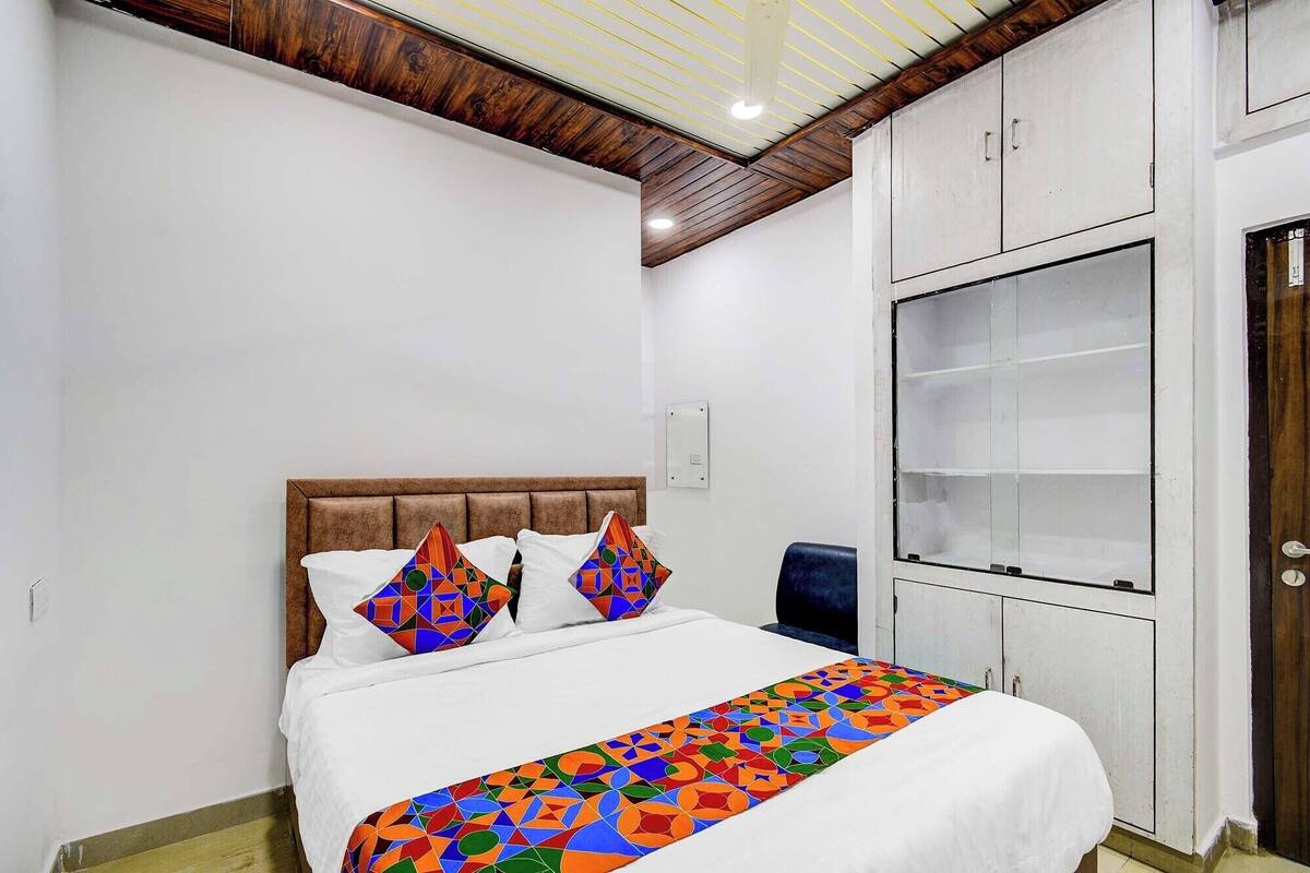 A bedroom with a bed, a headboard, a bedside table, a wardrobe, and a door.