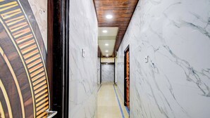 Un pasillo de mármol con techo de madera y una puerta al final.
