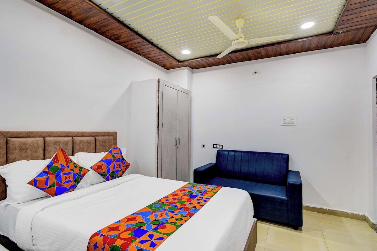 A bedroom with a bed, a blue sofa, a wardrobe, and a ceiling fan.