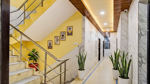A hallway with a marble floor, yellow walls, and a staircase with metal railings. - FabHotel Devara Grand - Kushaiguda Industrial Area, ECIL (Hyderabad)