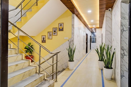 A hallway with a marble floor, yellow walls, and a staircase with metal railings.