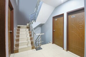 A staircase with metal railings leading to a landing, adjacent to two wooden doors with numbers 301 and 302. - Fabhotel Coco Tree (Gurugram)