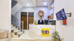 A hotel reception area with a marble counter, a reception desk, a staircase, and a potted plant. - Fabhotel Coco Tree (Gurugram)