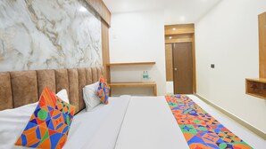 A hotel room with a marble headboard, a bed with colorful pillows, a wooden nightstand, and a patterned runner. - Fabhotel Coco Tree (Gurugram)