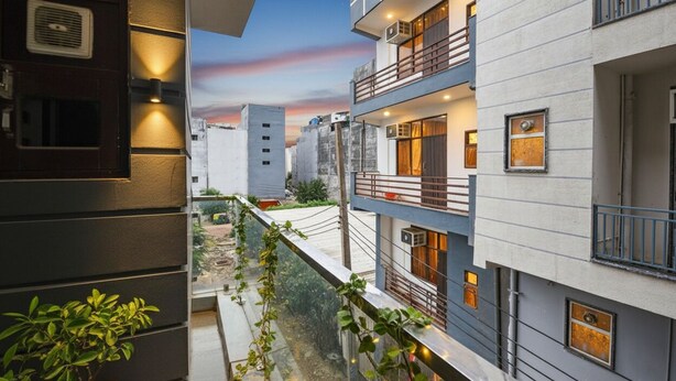 A modern building with multiple balconies, a visible outdoor area with plants, and a clear view of the sky. - Fabhotel Coco Tree (Gurugram)