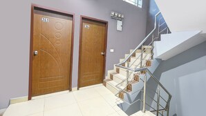 A modern interior with two wooden doors labeled 303 and 304, a metal staircase, and a window above the doors. - Fabhotel Coco Tree (Gurugram)