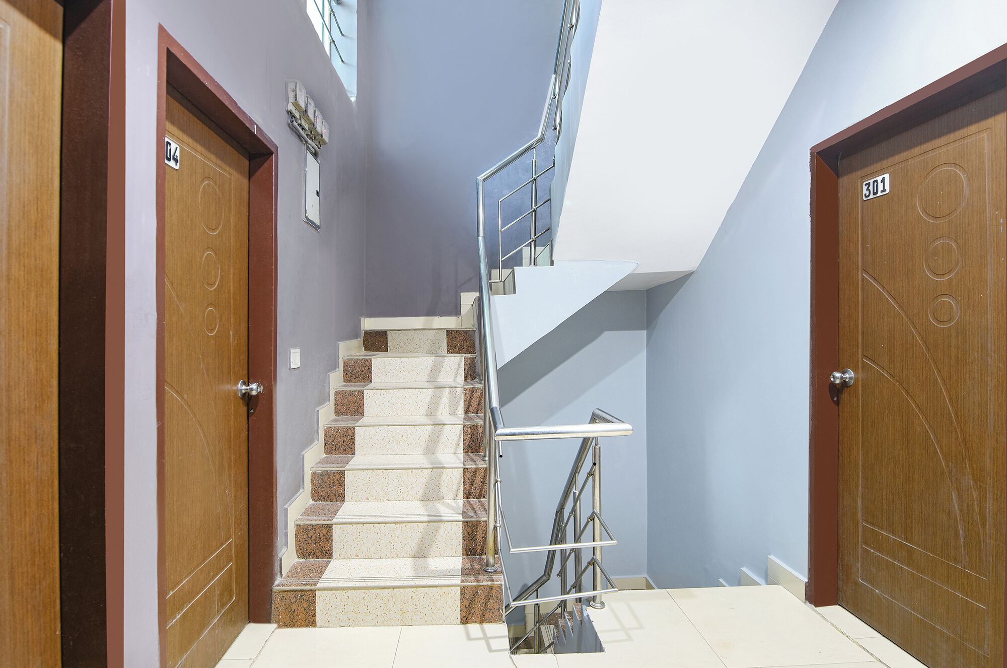 A modern interior with a staircase, wooden doors, and a metal handrail.