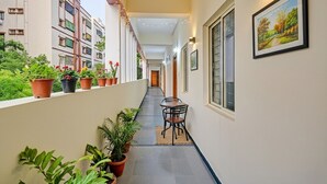A narrow corridor with potted plants and a table with chairs, leading to a door at the end. - Fabhotel Cube (Hyderabad)