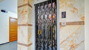 A hallway with a marble wall, a metal gate, and a wooden door. - Fabhotel Cube (Hyderabad)
