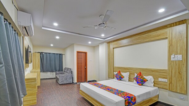 A hotel room with a bed, a chair, a ceiling fan, and a wooden headboard. - Fabhotel Cube (Hyderabad)
