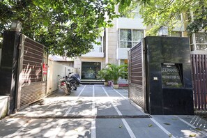 A gated entrance to a building with a motorcycle parked inside, potted plants, and a sign indicating the address. - Fabhotel Small Town (Sohna)
