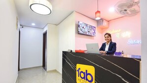 Una recepción con el logotipo de 'fab hotels', un televisor, un letrero de neón y un ventilador.