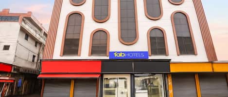 A building with a modern facade, a sign for 'fabHOTELS,' and storefronts with closed shutters.