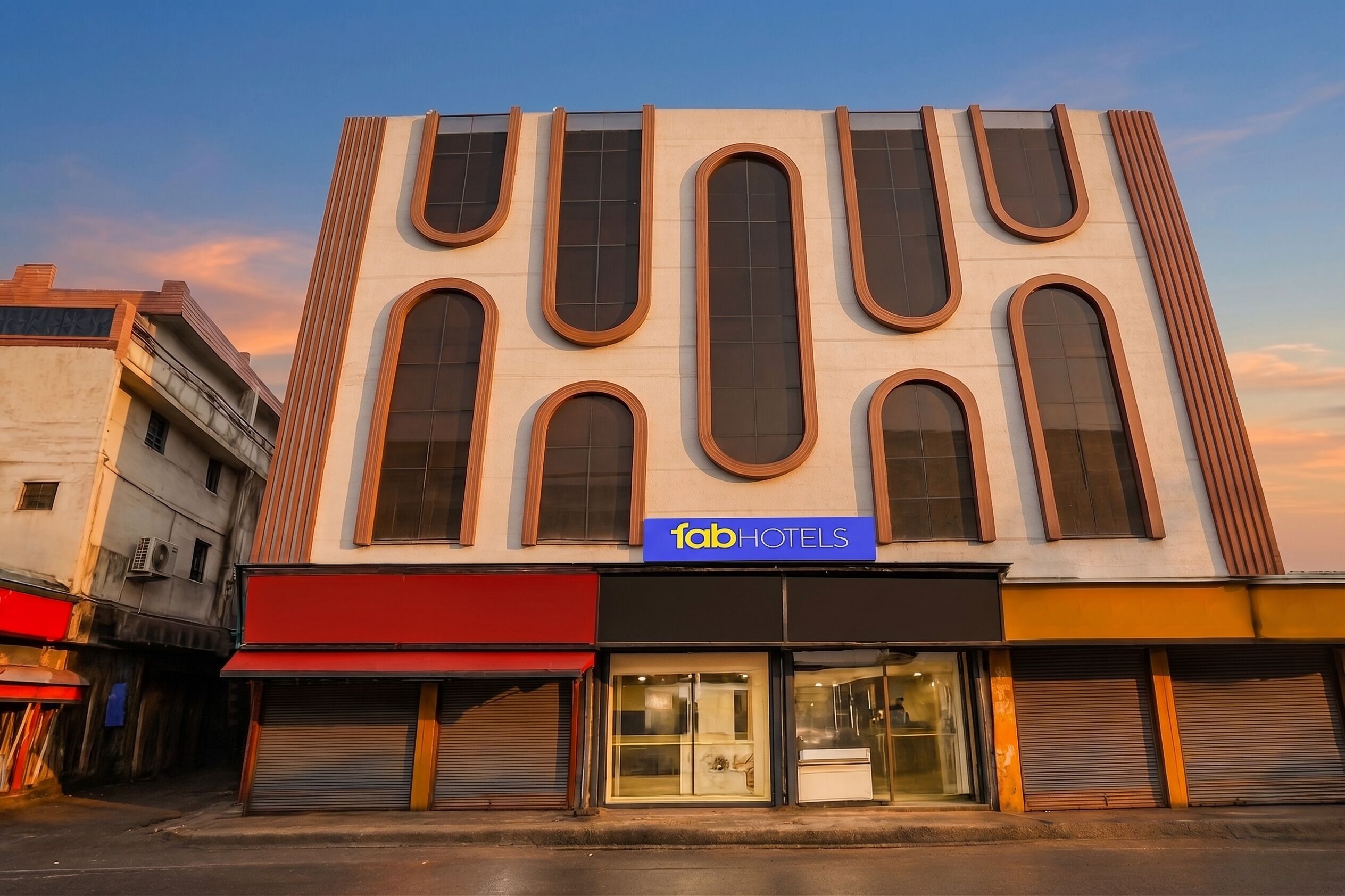 A building with a modern facade, a sign reading 'fabHOTELS,' and large windows.