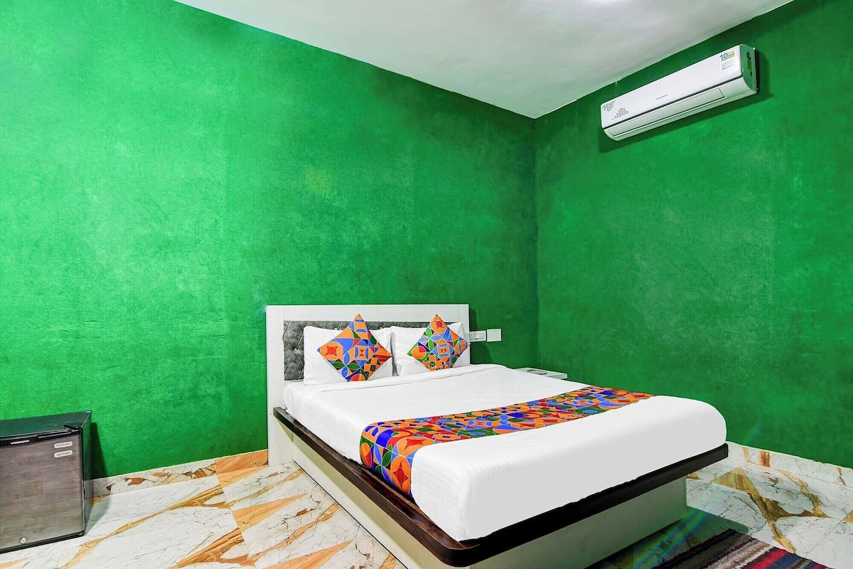 A room with a bed, green walls, and an air conditioning unit.