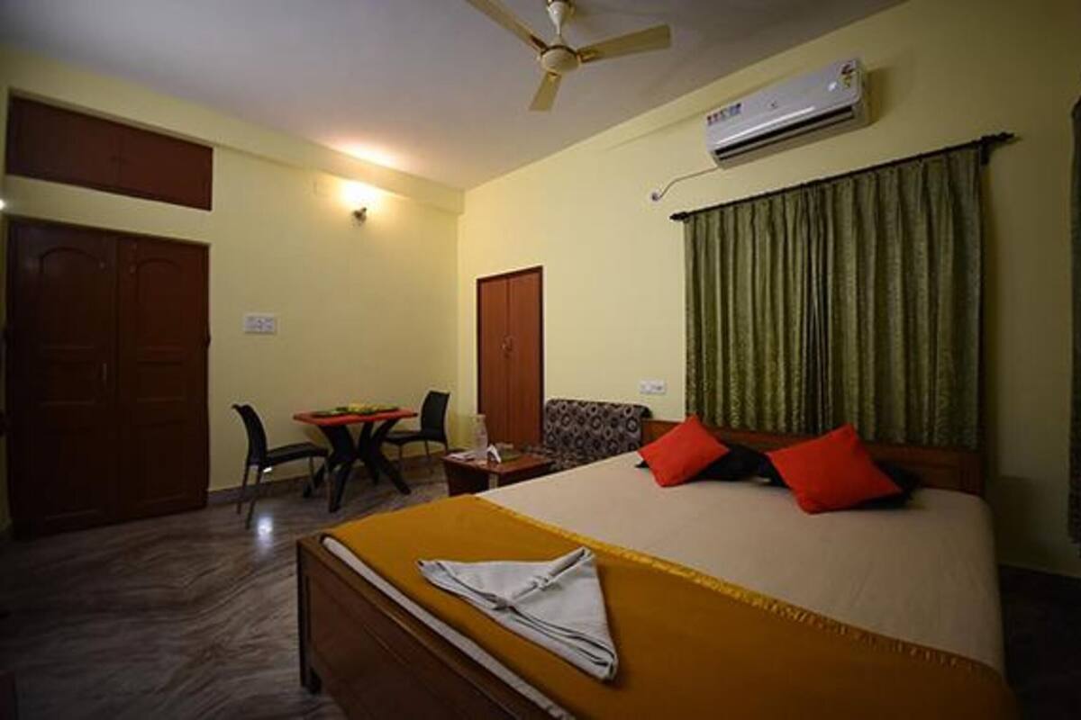 A hotel room with a bed, a desk, a chair, a wardrobe, and a ceiling fan.