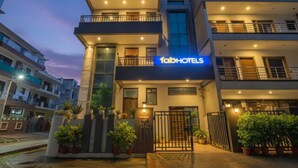 A modern building with a 'fabHOTELS' sign, featuring multiple balconies and a gated entrance.