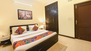 A hotel room with a bed, a wardrobe, a painting, and a door.