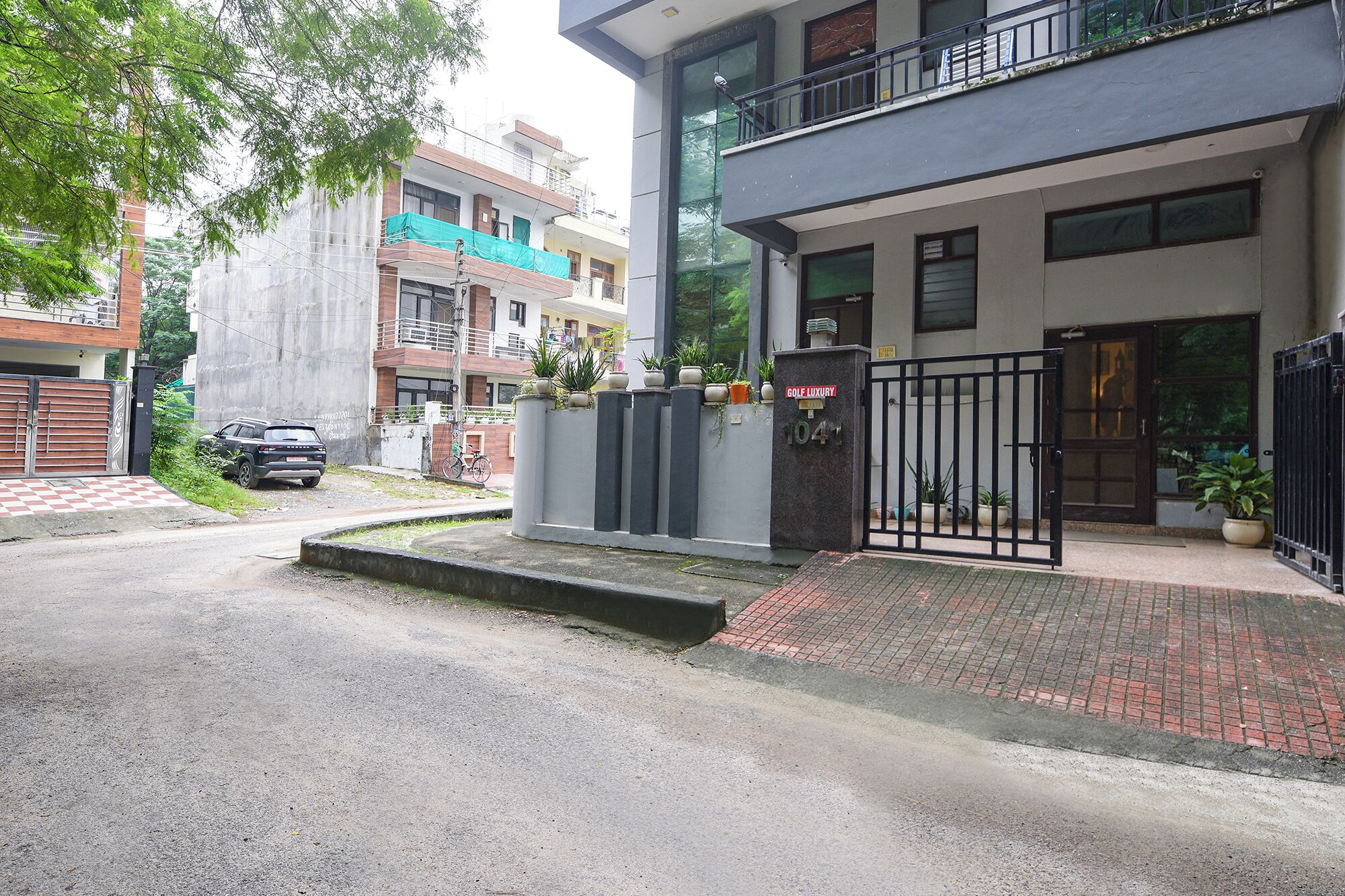 A modern building with a gated entrance, a balcony, and potted plants.