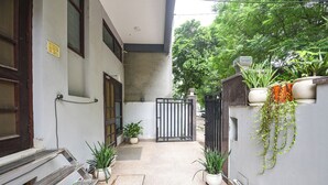 A narrow alleyway with a gated entrance, potted plants, and a bench.