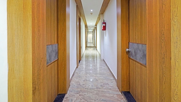 Un long couloir étroit, avec des portes en bois de chaque côté et un extincteur fixé au mur.