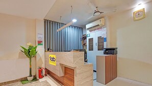 Un espace d’accueil d’hôtel avec un comptoir en marbre, un extincteur et un ventilateur de plafond.